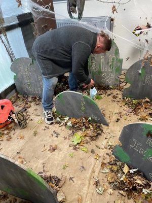 Un homme est afféré à préparer la décoration d&#039;Halloween, notamment ce cimetière fait avec des matériaux de récupération recyclés