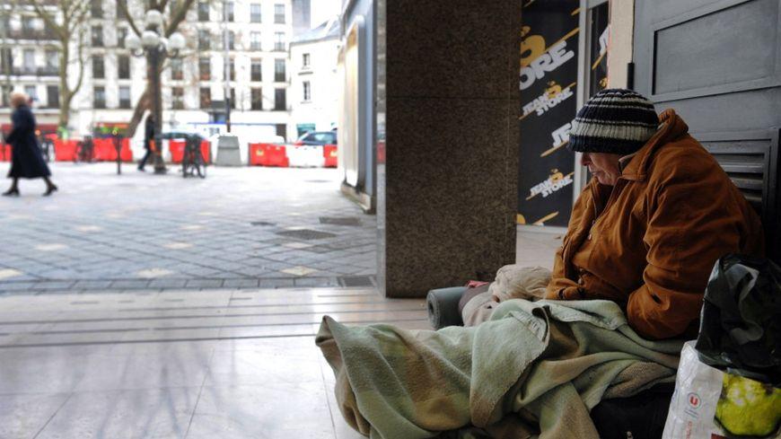 Un sans abri assis au sol dans une rue